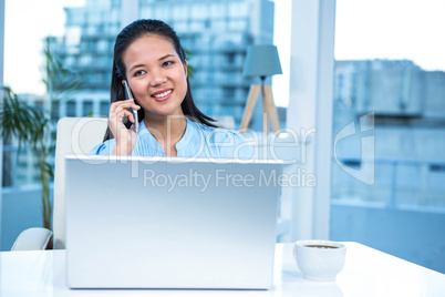 Smiling businesswoman on phone using laptop