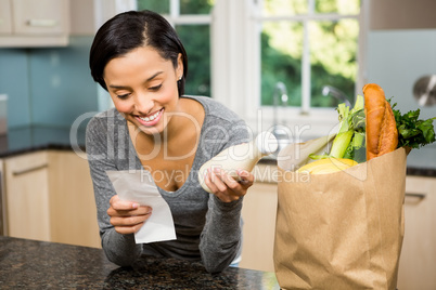 Smiling brunette holding receipt and milk