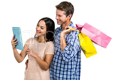 Couple with shopping bags looking at tablet PC