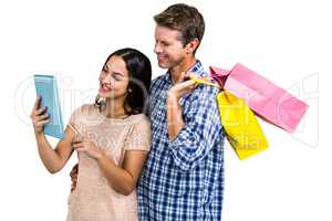 Couple with shopping bags looking at tablet PC