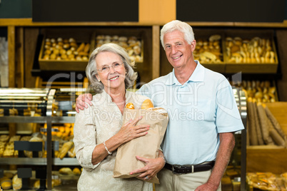 Smiling senior couple holding bakery bag