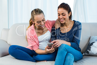 Friends texting on sofa