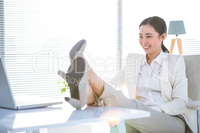 Businesswoman relaxing with legs on desk