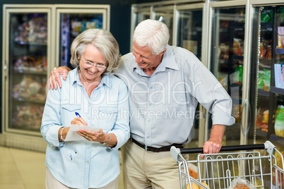 Smiling senior couple with cart checking list