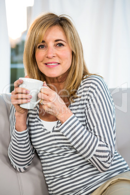 Woman holding cup on sofa