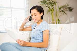 Smiling brunette on phone call holding sheets