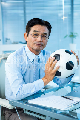 Asian businessman holding soccer ball