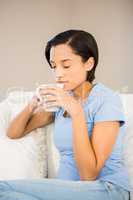 Relaxed brunette drinking by white cup