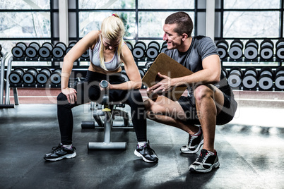 Fit woman doing dumbbells exercise with trainer