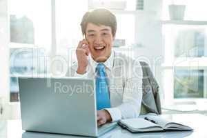 Smiling asian businessman working on laptop