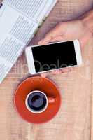 Overhead view of person using smart phone by coffee