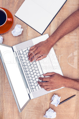 Overhead of stressed businessman using laptop