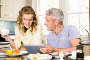 Happy couple using tablet and having breakfast