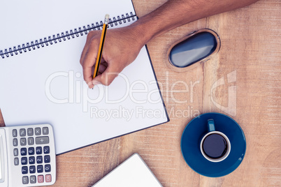 Cropped image of businessman writing on notebook by coffee at de