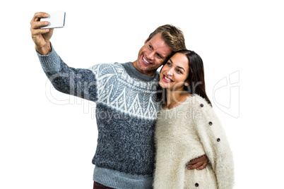 Cheerful young couple wearing warm clothing taking selfie