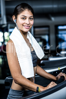 Smiling woman with headphones using treadmill