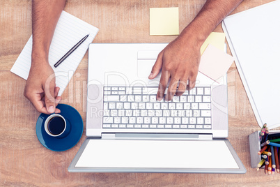 Businessman typing on laptop while having coffee