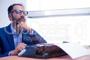 Businessman looking away while working on typewriter