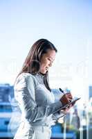 Smiling businesswoman writing on notebook