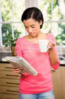 Standing brunette holding cup and newspaper