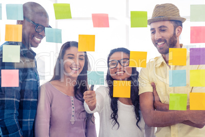 Happy creative people discussing over adhesive notes