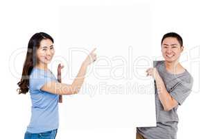 Portrait of happy young couple holding blank billboard