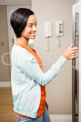 Smiling brunette with hand on refrigerator
