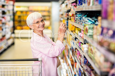 Senior woman taking a picture of product on shelf