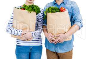 Mid section of couple holding grocery bags