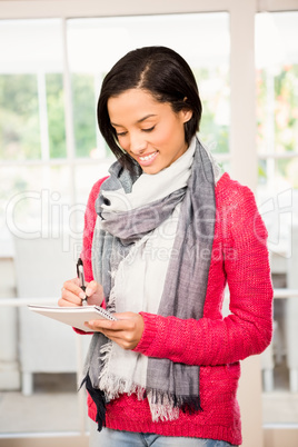 Smiling brunette writing on notepad