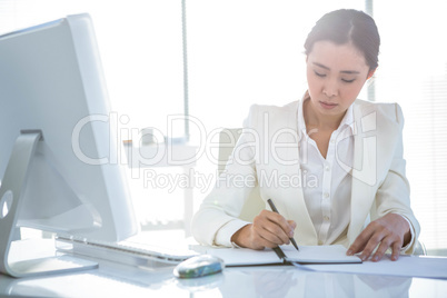 Businesswoman writing on diary on desk