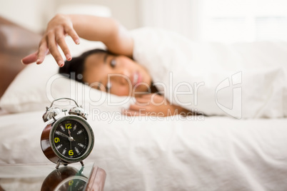 Alarm clock against brunette on bed