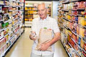 Senior man with grocery bag using smartphone