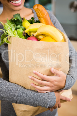Smiling brunette holding grocery bag
