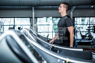 Concentrated muscular man using treadmill