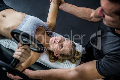 Fit woman doing dumbbells exercise with trainer