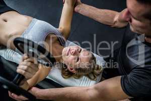 Fit woman doing dumbbells exercise with trainer