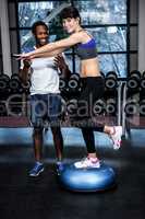 Fit woman with trainer exercising with bosu