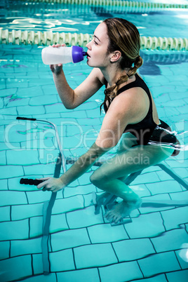 Fit woman cycling while drinking water