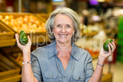 Senior woman holding two avocado