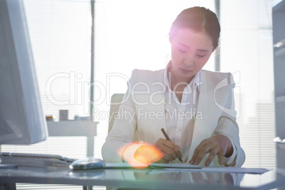 Businesswoman writing on diary on desk