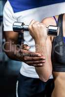 Cropped image of male trainer assisting fit woman