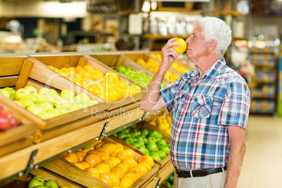 Smiling senior man smelling orange Smiling senior man smelling orange