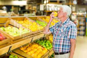 Smiling senior man smelling orange