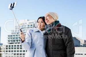 Playful couple taking selfie against building