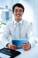 Smiling asian businessman using his tablet