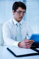 Serious asian businessman using his tablet