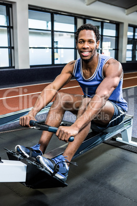 Muscular man using rowing machine