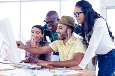 Cheerful businessman explaining colleagues over computer