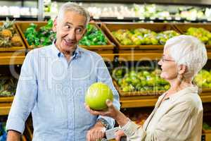 Happy senior couple looking a fruit